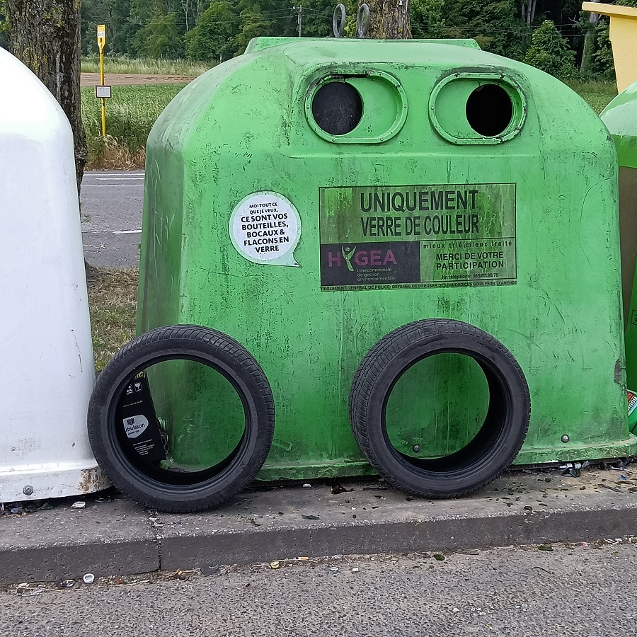 Pneus usagés abandonnés devant des bulles à verre